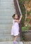 Portrait of little asian child posing at stair railing. Pigtail girl looking at camera