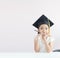 Portrait little Asian girl is wearing graduate hat holding pencil sitting thinking something and smile with happiness select focus
