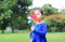 Portrait of little Asian kid girl blowing wind turbine in the summer garden