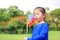 Portrait of little Asian kid girl blowing wind turbine in the summer garden