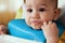 Portrait of little baby boy eating food. Baby with a spoon in feeding chair. Cute baby eating first meal