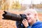 Portrait of little blond boy takes pictures on a SLR camera. Autumn Park