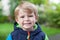 Portrait of little blond toddler boy smiling outdoors