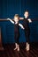 Portrait of little blonde curly ballerina and small boy dancer in black leotard practicing at ballet barre at dance studio. Kids