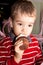 Portrait of a little boy eating tasty cocoa muffin with whipped topping