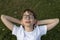 Portrait little boy with glasses and white T-shirt with closed eyes. Schoolboy rests on green lawn. Summer holidays