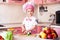 Portrait of little boy in the hat of the chef and an apron. Little chef cooks in the kitchen.Portrait of cute boy helping at