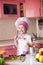 Portrait of little boy in the hat of the chef and an apron. Little cooks chef in the kitchen cooking . Keep a ladle and smiling