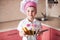 Portrait of little boy in the hat of the chef and an apron. Little cooks chef in the kitchen preparing spaghetti.