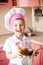 Portrait of little boy in the hat of the chef and an apron. Little cooks chef in the kitchen preparing spaghetti. Emotional