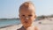 Portrait of little boy on sea beach. Child squints at the bright sun