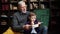 Portrait of little boy sitting on knees of his grandfather and reading an interesting book together.