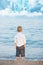 Portrait with little boy standing on the beach with blurry background by the sea and fantasizes about castles in the air