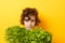Portrait of little boy standing isolated on yellow background and enjoying delicious lettuce while looking at camera