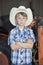 Portrait of a little boy wearing cowboy hat while standing with arms crossed against machine