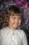 Portrait of a little brunette girl with curls with a white sweater on a floral background