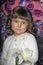 Portrait of a little brunette girl with curls with a white sweater on a floral background