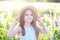 Portrait of a little brunette girl with long hair having fun on a stunning blooming meadow of lupines on a golden sunset backgroun
