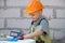 Portrait of little builder in hardhats with instruments for renovation on construction. Builder boy, carpenter kid with