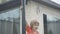 Portrait of little Caucasian boy climbing on basketball hoop at home. Relaxed cheerful kid having fun outdoors