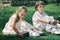 Portrait of little caucasian girl and boy in casual clothes sitting on the grass