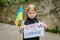 Portrait little child calls no war, raises banner with inscription Stop war in Ukraine and blue-yellow flag of Ukraine. Peace,