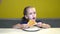 Portrait of little child girl eat slice of pizza at cafe with yellow walls. In slow motion