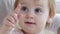 Portrait of little curious female child with beautiful big gray eyes points finger closeup