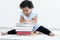 Portrait of Little cute African chubby kid girl use left hand writing on paper on stack of textbooks and sitting on floor