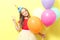 Portrait of a little cute girl in a festive cap and with balloons