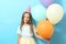 Portrait of a little cute girl in a festive cap and with balloons