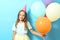 Portrait of a little cute girl in a festive cap and with balloons