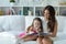 Portrait of little cute girl reading book with mother while sitting on safe