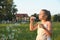 Portrait of little cute girl which blows soap bubbles smiling. Outdoors on a background of green grass and forest