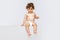 Portrait of little cute toddler boy, baby in diaper joyfully sitting isolated over white studio background. Happy