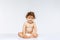 Portrait of little cute toddler boy, baby in diaper joyfully sitting isolated over white studio background. Happy