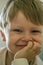 Portrait of a little fair-haired boy with his chin propped on his hand and looking at the camera.