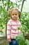 Portrait of the little girl against the background of plants of tomatoes in the greenhouse