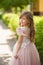 Portrait of a little girl with blond curls in a gentle dress with ostrich feathers