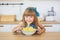 Portrait of a little girl in a blue dress funny eats a spaghetti from a dish and smiling