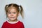 Portrait of little girl with blue eyes biting lower lip looking at camera