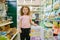 Portrait of little girl child standing nearby cage for rodent at pet shop