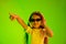 Portrait of little girl in headphones on green background in neon light