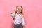 Portrait of little girl in headphones. schoolgirl in uniform. pink background