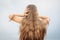 portrait of a little girl with long hair, back, covers her ears with her hands