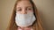 Portrait of little girl with medical face mask during self isolation. Sad female child wear protective mask from virus