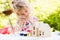 Portrait of little girl paints wooden model of house