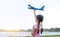 Portrait of little girl raise up a blue toy airplane flying on air in the nature garden. Back view
