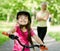 Portrait of a little girl riding her bike ahead of her mother