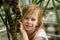 Portrait, little girl seven years, sitting next palm tree